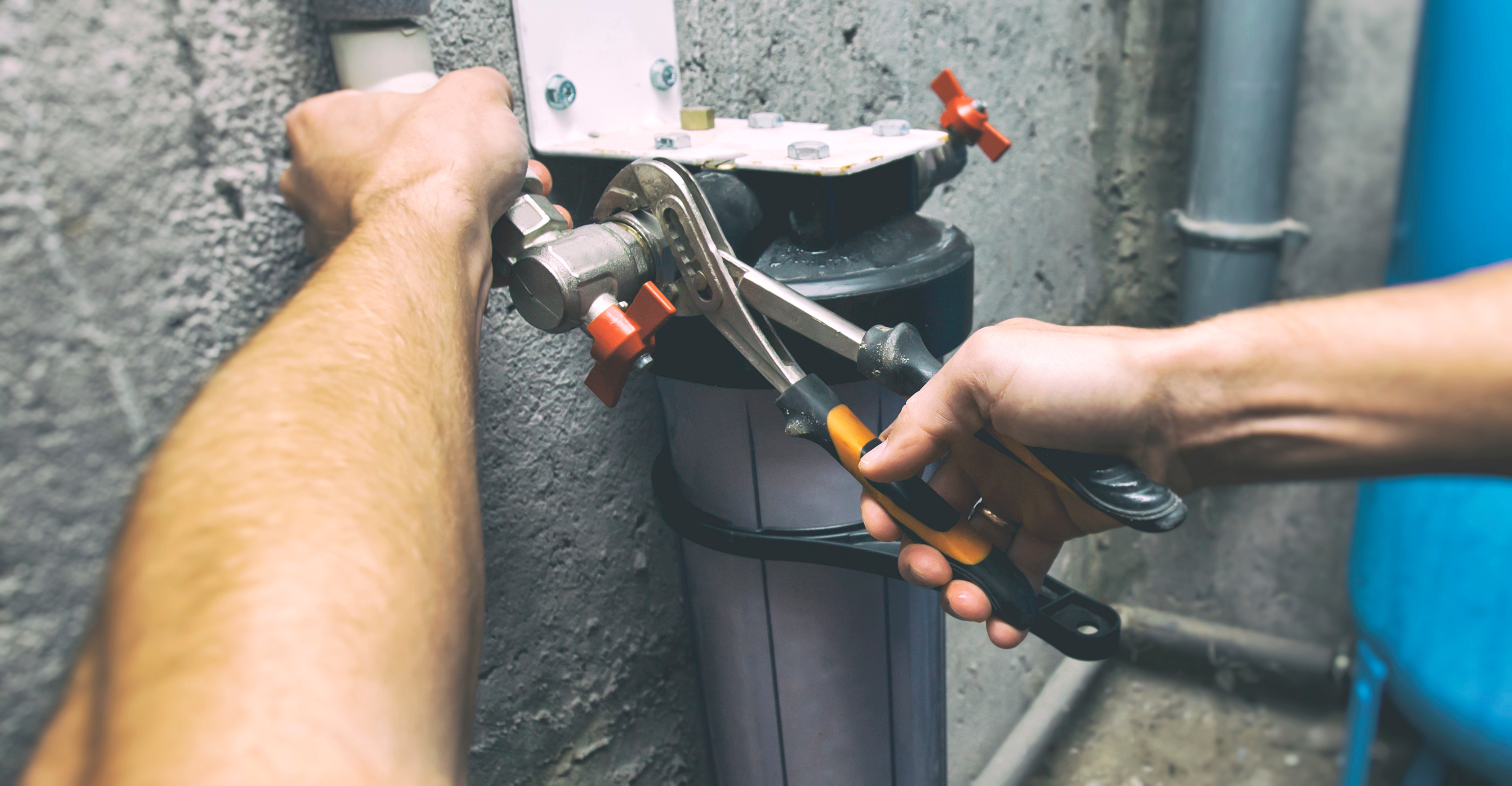 The plumber is repairing the water filter in the  basement